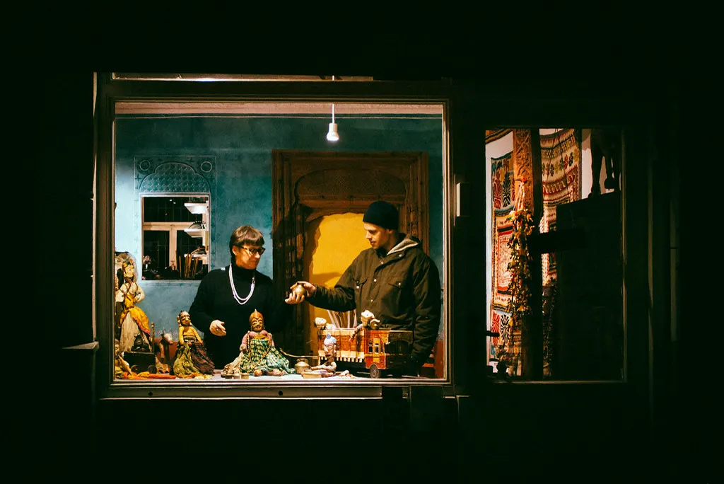 Vitrine iluminada de loja à noite com duas pessoas olhando produtos, como o curioso que só olha