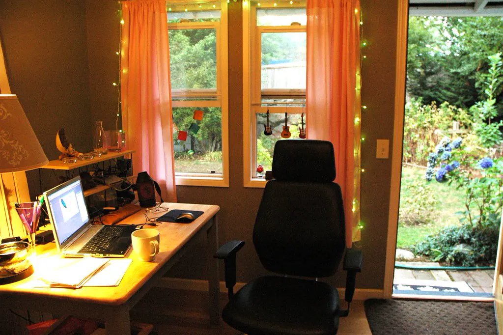 Escritório em casa com notebook aberto sobre a mesa e cadeira de trabalho, onde o dono cuida do site da empresa