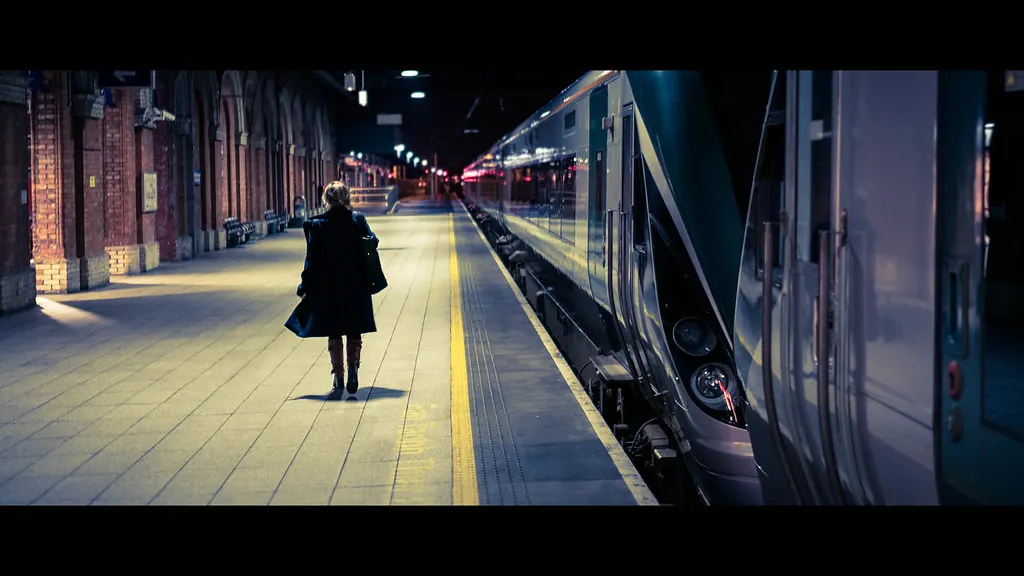 Mulher caminhando sozinha numa estação de trem à noite, fora do horário comercial