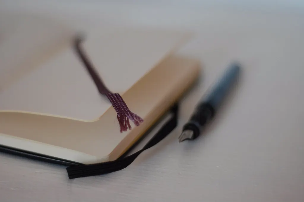 Caderno aberto e caneta tinteiro sobre a mesa, prontos para escrever a base de conhecimento para chatbot da empresa