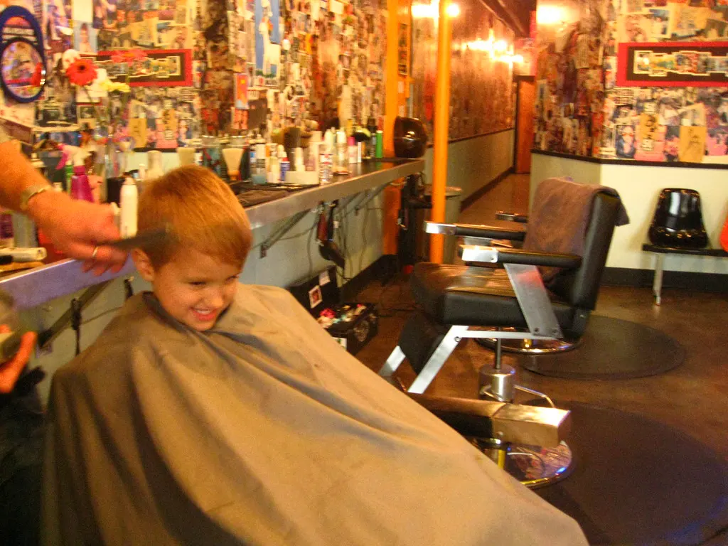 Criança cortando o cabelo em uma barbearia, exemplo de negócio local que precisa de uma boa bio do Instagram para empresa