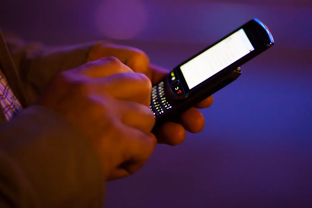 Mãos digitando no celular à noite, momento em que o cliente compara a bio do Instagram de várias empresas