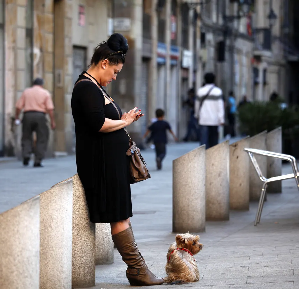 Mulher na rua consultando o celular, como o cliente que espera uma resposta rápida do chatbot para WhatsApp da empresa