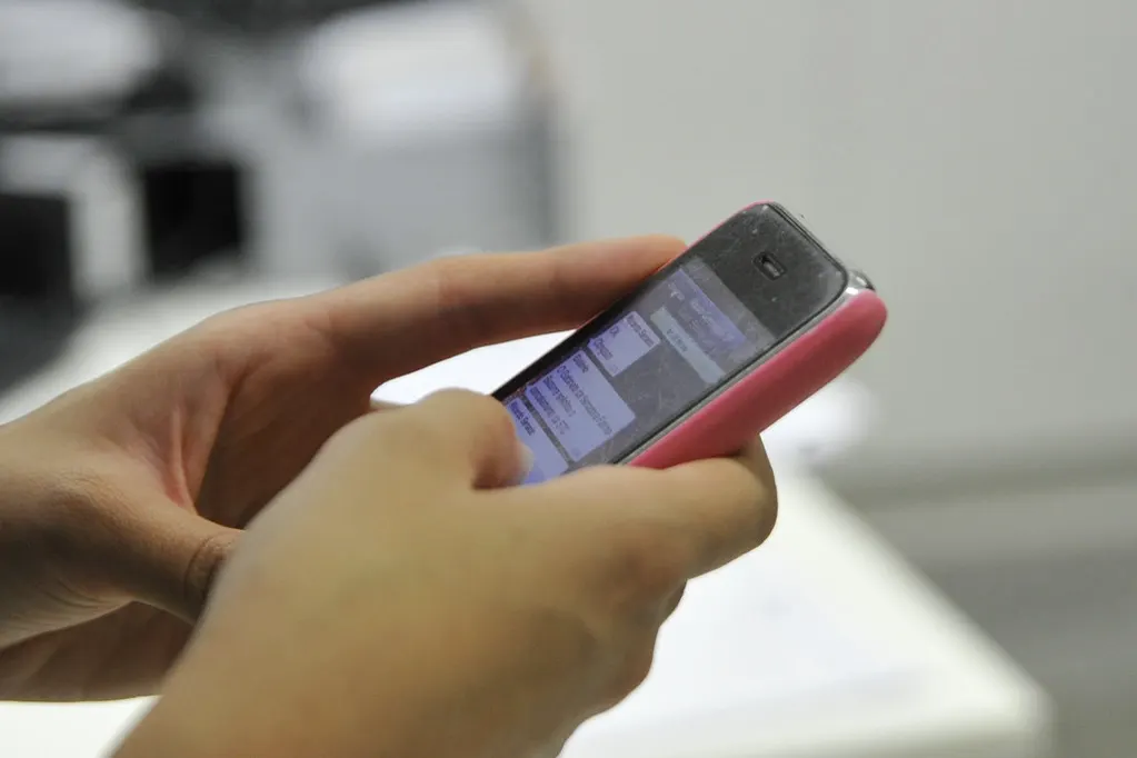 Mãos digitando no celular, como em um atendimento afetado pela cobrança do WhatsApp Business