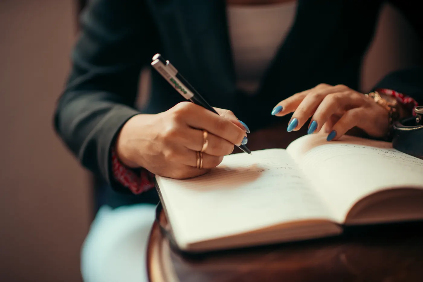Mulher anotando valores em um caderno, controlando o ticket médio e o custo de cada venda