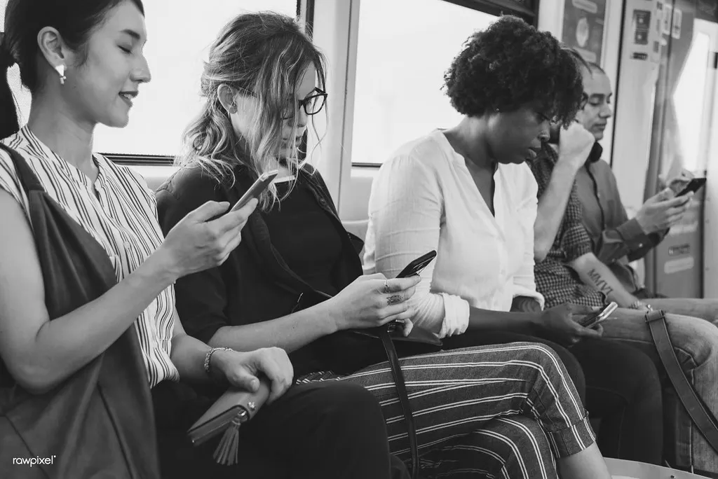 Pessoas sentadas no metrô usando o celular, mostrando como as redes sociais fazem parte da rotina do brasileiro