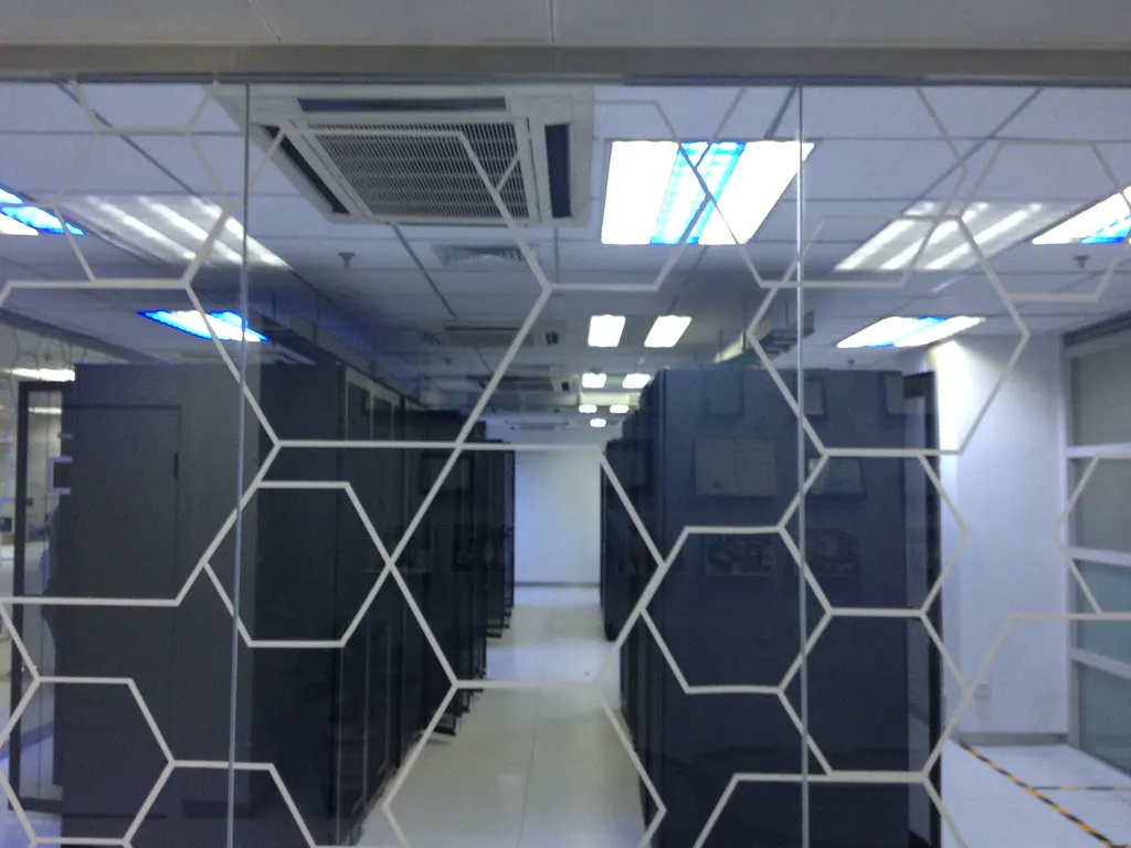 Corredor de um data center visto através de um vidro, ilustrando o processamento local de dados do Gemini Enterprise no Brasil