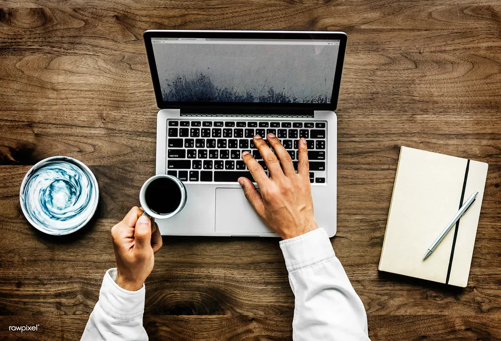 Vista de cima de uma pessoa digitando no notebook com café, pesquisando anúncios no Google para a empresa