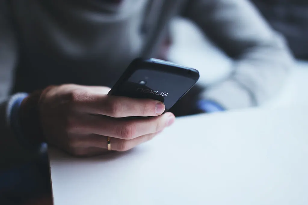 Pessoa segurando o celular sobre a mesa, como o cliente que pesquisa empresas pelo GPT-6 no ChatGPT