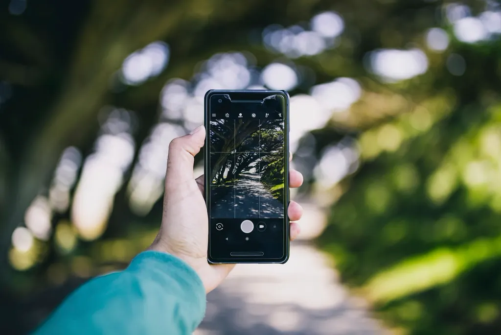 Pessoa segurando o celular para fotografar uma cena e criar um post antes de impulsionar ou criar anúncio