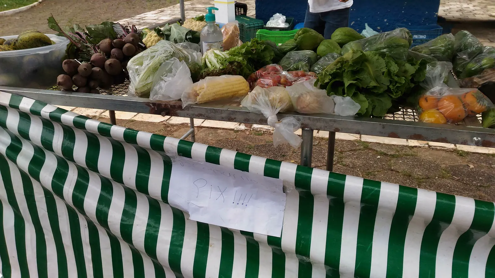 Banca de feira com verduras e um aviso escrito à mão dizendo que aceita Pix