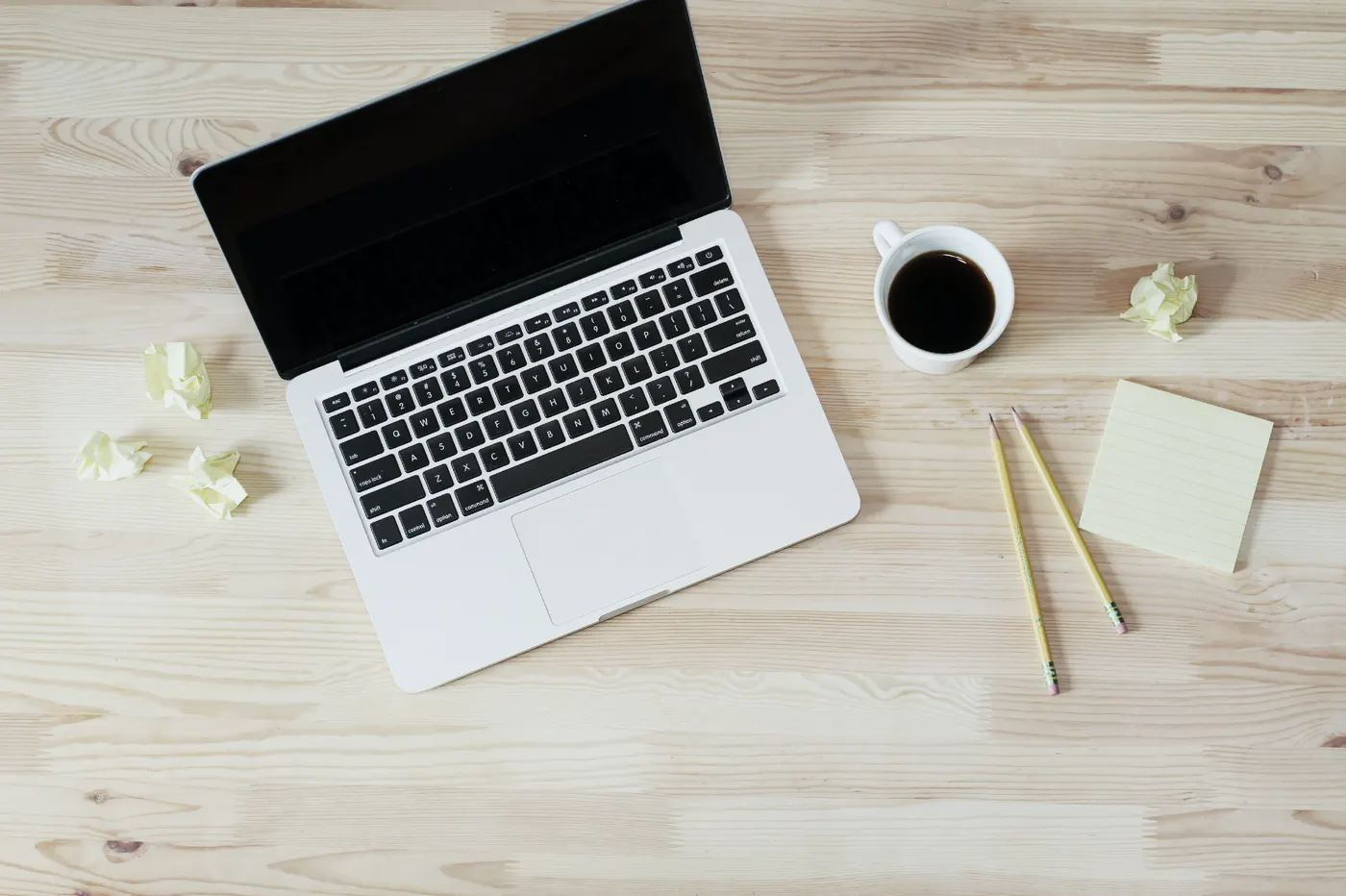 Notebook, xícara de café, lápis e bloco de notas sobre a mesa, usados para montar o modelo de planejamento
