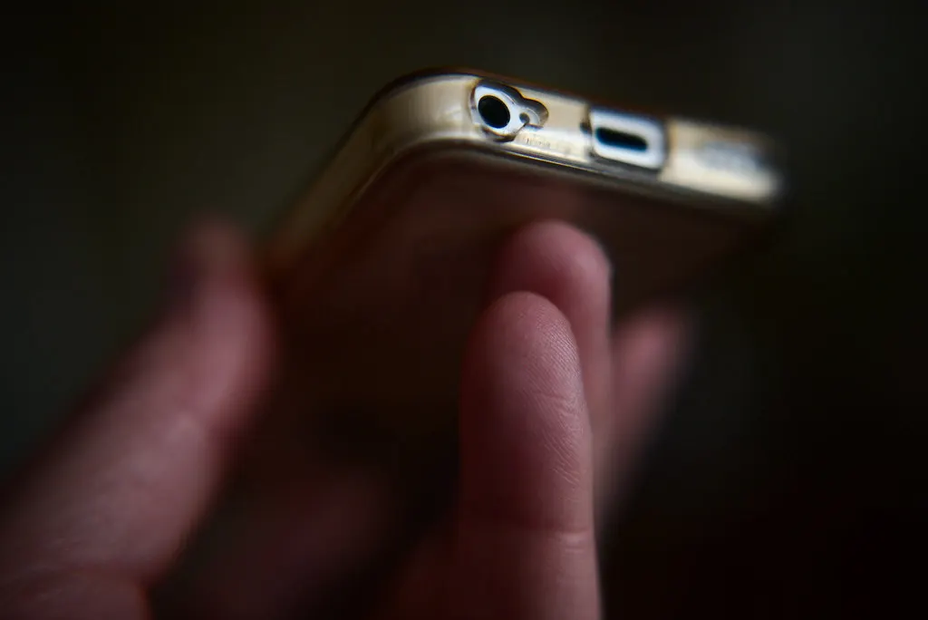 Mão segurando um celular em um ambiente escuro, conferindo quanto custa anunciar no Instagram por mês
