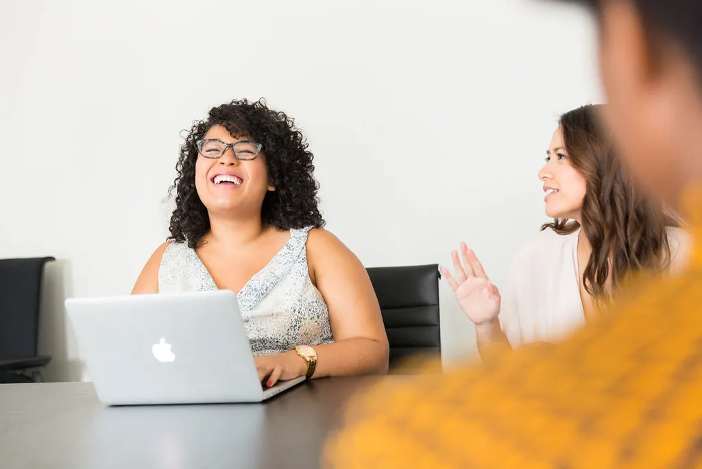 Mulher sorrindo em frente a um notebook durante reunião sobre quanto custa um site profissional