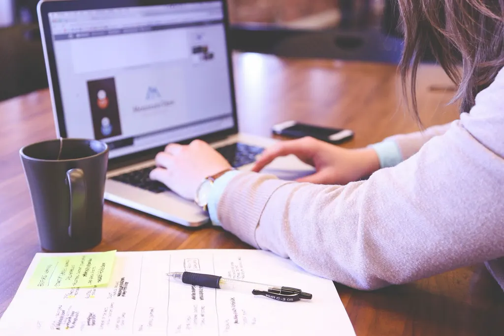 Mulher trabalhando no notebook com anotações ao lado, revisando o orçamento do Google Ads da empresa