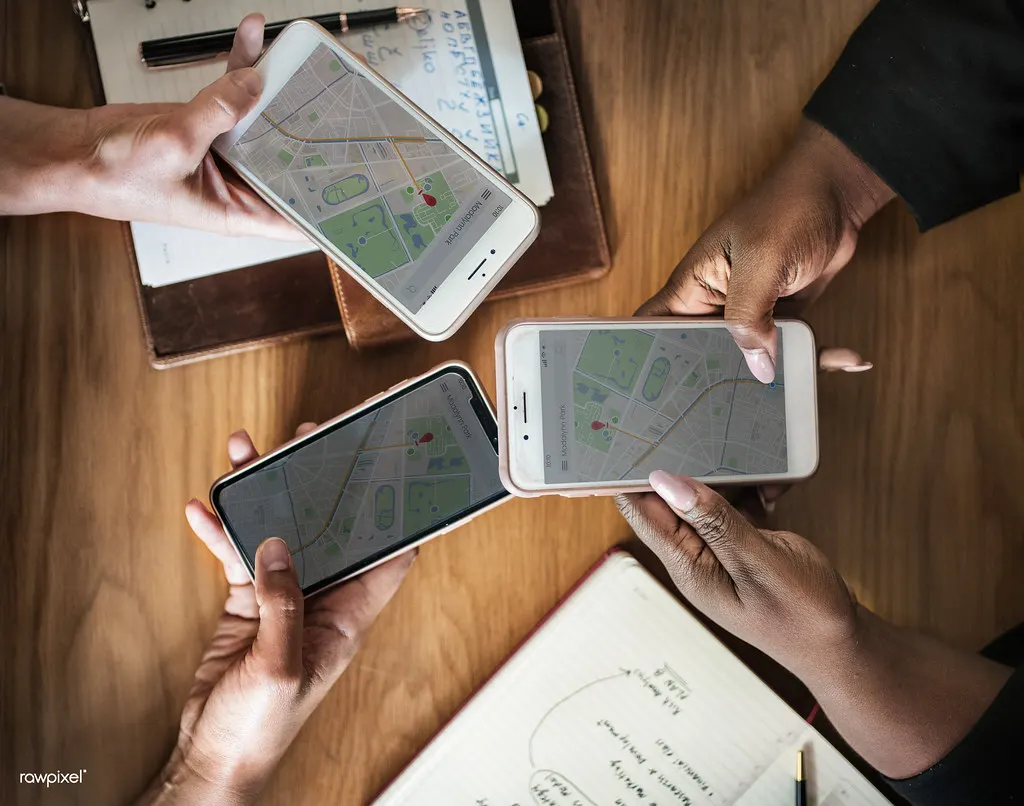 Pessoas segurando celulares com mapas abertos, mostrando quanto tempo demora para aparecer no Google Maps