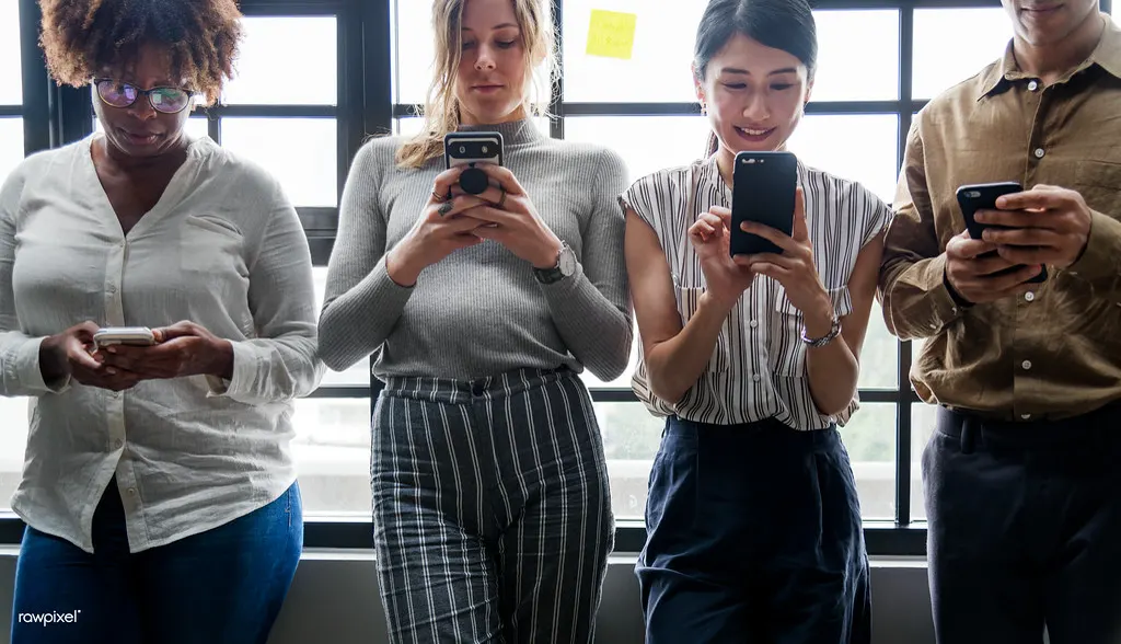 Grupo de pessoas olhando o celular, como os futuros clientes que leem a resposta da empresa a uma avaliação negativa