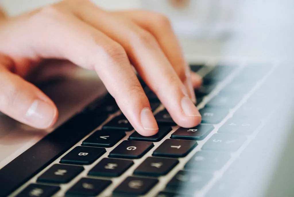 Mão digitando no teclado do notebook, representando tarefas repetitivas para automatizar no dia a dia da empresa